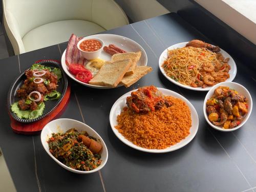 a table topped with bowls of different types of food at Emmaag Hotel, Ibadan in Ibadan
