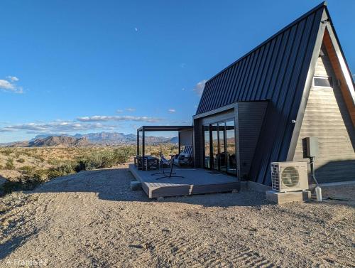 a small cabin with a deck with a view of the desert at Stardust Big Bend Luxury A-Frame#5 great views in Terlingua