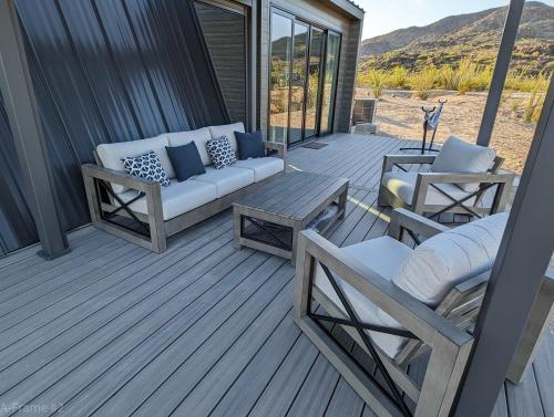 a porch with a couch and a table and chairs at Stardust Big Bend Luxury A-Frame#5 great views in Terlingua