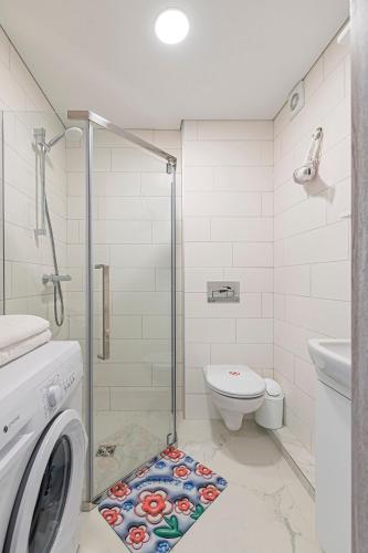 a bathroom with a shower and a washing machine at Pramonės Apartment #5 by PoloApartments in Kaunas