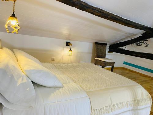 a bedroom with a large white bed in a attic at Adega dos Moinhos in Pereiro