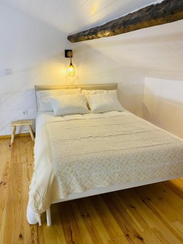 a bedroom with a white bed with a wooden floor at Adega dos Moinhos in Pereiro