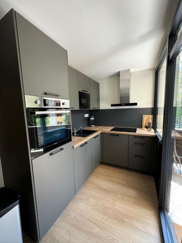une cuisine avec des placards blancs et une grande fenêtre dans l'établissement Appartement T3 Pra Loup 1600, à Pra-Loup