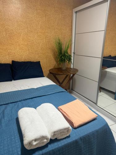 a bedroom with a blue bed with towels on it at Quarto em AP compartilhado Ponta da areia in São Luís