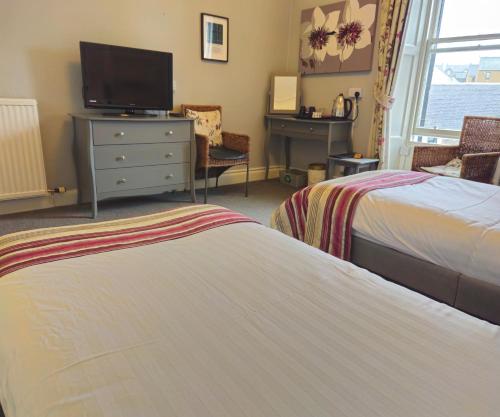 a bedroom with two beds and a dresser with a tv at The County Hotel - Self Check-In, Ultra Fast WI-FI, Free Parking, Central Location in Selkirk