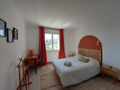 a bedroom with a bed and a window with red curtains at Villa au calme, tout confort clim piscine wifi 7 personnes in Caunes-Minervois