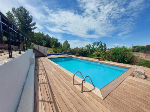 - une piscine sur une terrasse en bois à côté d'un bâtiment dans l'établissement Villa au calme, tout confort clim piscine wifi 7 personnes, à Caunes-Minervois