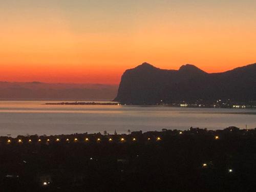 a sunset with a view of the water and mountains at La vecchia quercia in Carini