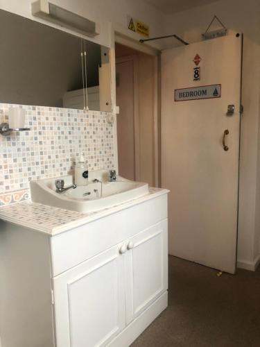 Un baño con un lavabo blanco y un espejo. en Beachcomber Guesthouse, en Weymouth
