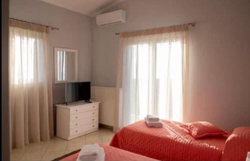 a bedroom with two beds and a television and a dresser at Elenas Villas in Kyllini