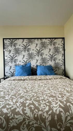 une chambre avec un grand lit avec des oreillers bleus dans l'établissement Appartement Cosy Clinique Mathilde, à Rouen