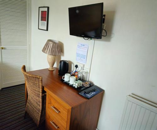 a room with a desk with a television on a wall at The County Hotel - Self Check-In, Ultra Fast WI-FI, Free Parking, Central Location in Selkirk