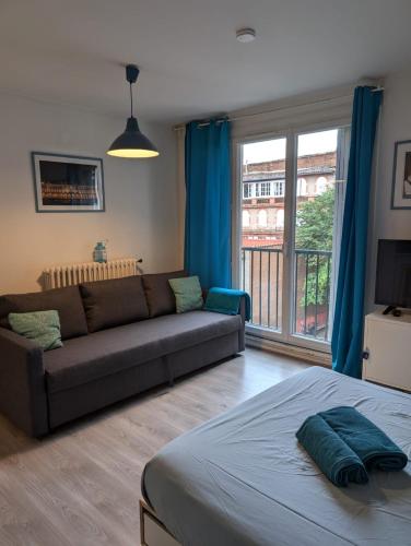 un salon avec un canapé et une grande fenêtre dans l'établissement Ombre Bleue, à Toulouse