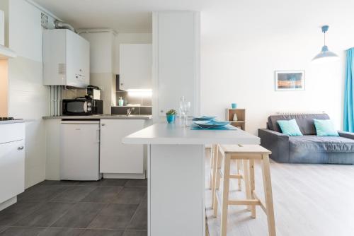 d'une cuisine et d'un salon avec des placards blancs et une table. dans l'établissement Ombre Bleue, à Toulouse