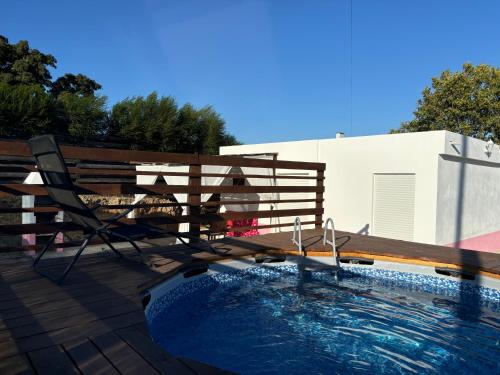 a wooden bench sitting next to a swimming pool at Herdade Palma T1p in Moita