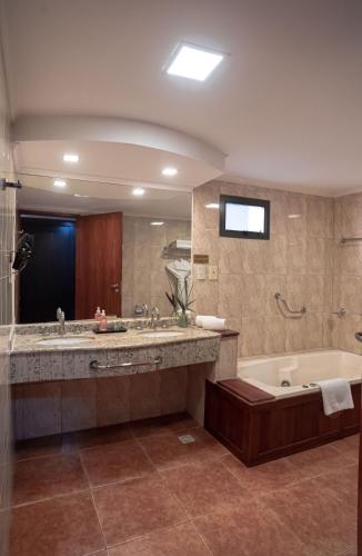 a large bathroom with a tub and a large sink at Hotel Saint George in Puerto Iguazú