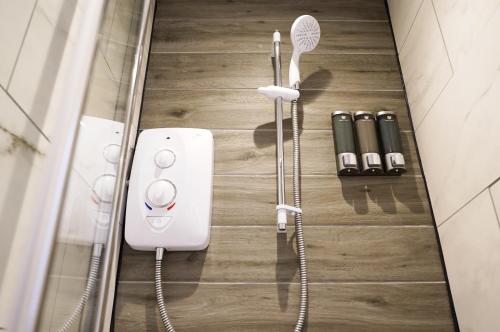 a shower in a bathroom with a hair dryer and other items at Church Street Studio Apartment in Keighley