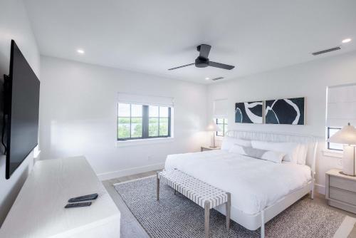 a white bedroom with a bed and a tv at Brand New Catchlight House with Private Pool in Key West