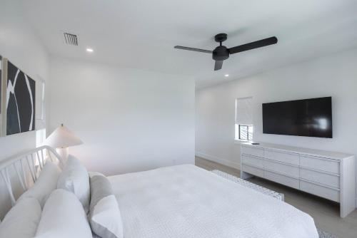 a white bedroom with a bed and a flat screen tv at Brand New Catchlight House with Private Pool in Key West