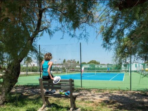 a woman sitting on a bench at a tennis court at La cabane des rêves in Pérols