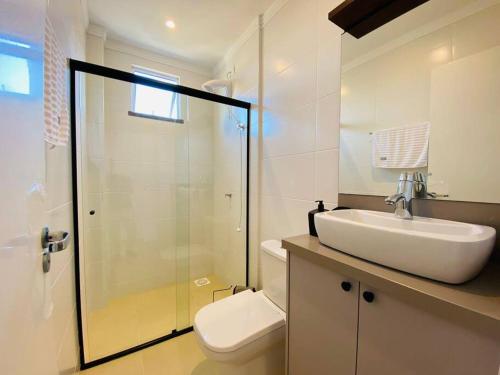 a bathroom with a toilet and a sink and a shower at Apartamento novo - 400m do mar Bombinhas in Bombinhas