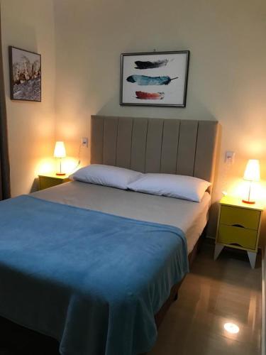 a bedroom with a bed with blue sheets and two lamps at chalé vista para montanha in Penedo
