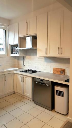 une cuisine avec des armoires blanches et un four à plaques de cuisson dans l'établissement Le RUBIS - 2 Chambres - Centre ville, à Amiens