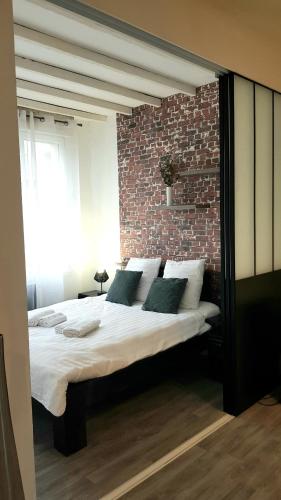 une chambre avec un grand lit avec un mur de briques dans l'établissement Le RUBIS - 2 Chambres - Centre ville, à Amiens