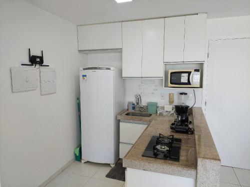 a kitchen with white cabinets and a refrigerator at Marinas da Barra - Flat Beira-Mar em Barra de Jangada por Yolo in Recife