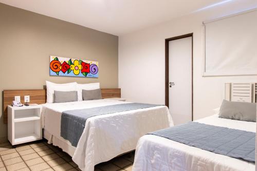 a bedroom with two beds and a painting on the wall at Citi Hotel Express Caruaru in Caruaru
