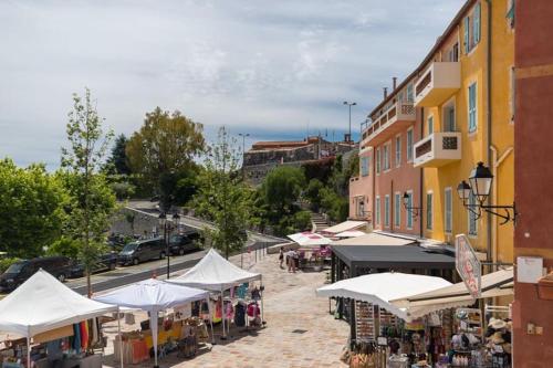 un marché en plein air avec des parasols blancs dans une rue dans l'établissement Superbe Duplex avec vue !, à Villefranche-sur-Mer