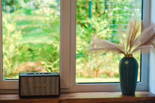 a green vase with a plant in it next to a window at Home Stay Juniper in Jelgava