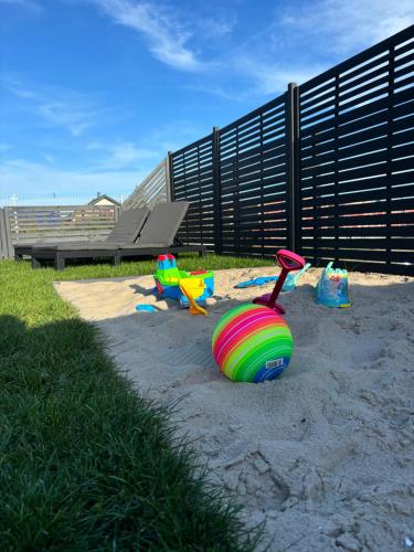 a sandbox with toys in the sand in a park at Wodne Widoki - domek letniskowy z jacuzzi in Dziwnówek