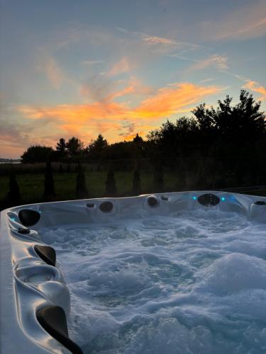 a jacuzzi tub filled with water at sunset at Wodne Widoki - domek letniskowy z jacuzzi in Dziwnówek