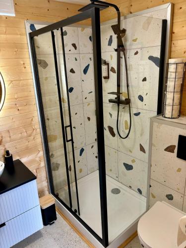 a bathroom with a shower with a rock wall at Wodne Widoki - domek letniskowy z jacuzzi in Dziwnówek