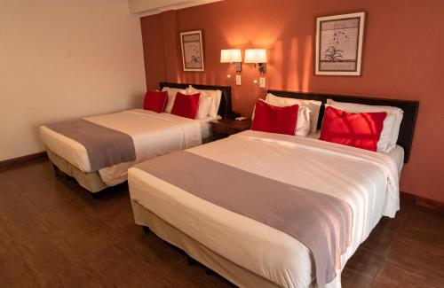 two beds in a hotel room with red pillows at Hotel Saint George in Puerto Iguazú