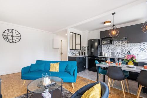 un salon avec un canapé bleu et une cuisine dans l'établissement Appartement de Standing, à Saint-Denis