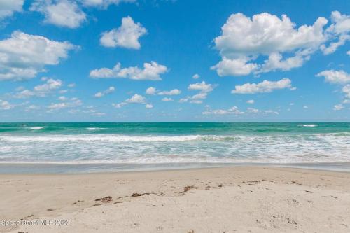 a beach with the ocean and clouds in the sky at Your Space Coast Home - 30 Seconds to Sand in Cape Canaveral