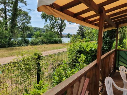 a wooden deck with a table and chairs and a fence at Les flots de Condrieu - VIA -RHÔNA -8 pers, et vue sur Rhône-BBQ in Condrieu