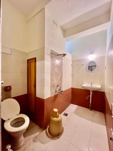 a bathroom with a toilet and a sink at Hotel Down Town in Manipala