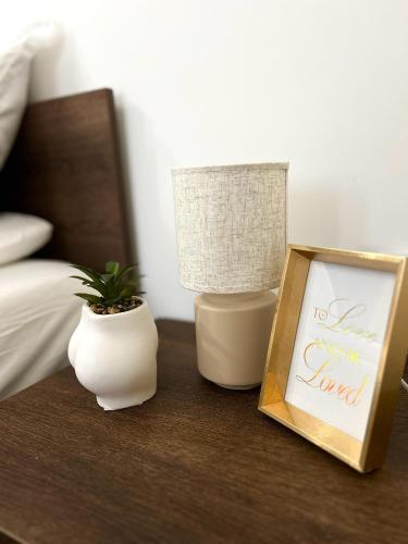 a table with a lamp and a sign and a plant at Millie's apartments in Ćuprija