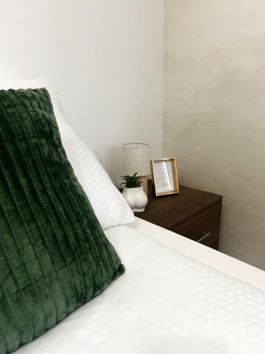 a bed with a green pillow and a night stand at Millie's apartments in Ćuprija