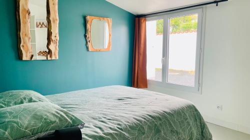 - une chambre avec des murs bleus et un lit avec un miroir dans l'établissement Petite maison en bord de mer, à Longeville-sur-Mer