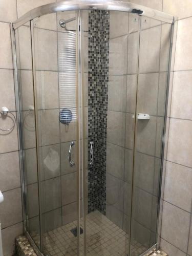 a shower with a glass door in a bathroom at Cass Villa 25 Kimberley in Kimberley