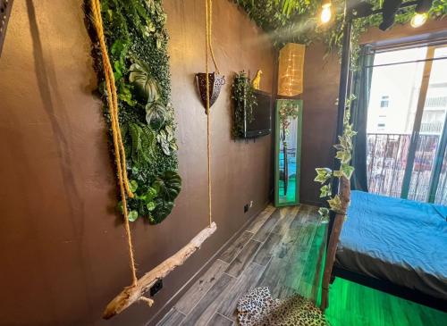 une chambre avec des plantes sur le mur et une chambre avec dans l'établissement La Tanière de Mowgli - Plage du môle, au Cap d'Agde