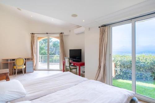 una camera da letto con un letto, una scrivania e una finestra di Logement entier villa de luxe avec vue mer a Théoule-sur-Mer