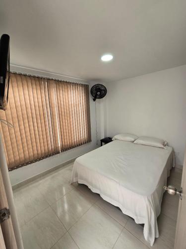 a bedroom with a white bed and a window at Apartahotel Nueva Imagen in Roldanillo