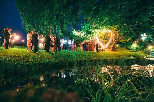 a group of people standing near a pond at night at Kučuru dzirnavas in Lautere