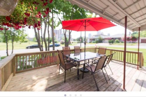 a table and chairs with a red umbrella on a deck at Niagara SkyLine Park And Walk To The Falls & Wonderful Free Breakfast Deliverd Daily to the Rental in Niagara Falls