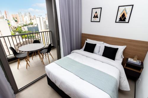 a bedroom with a bed and a balcony with a table at 360 VN Turiassú by Housi in Sao Paulo